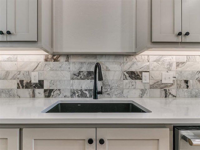 kitchen with gray cabinets, light countertops, a sink, and decorative backsplash