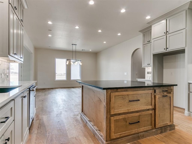 kitchen with light wood-type flooring, arched walkways, and recessed lighting