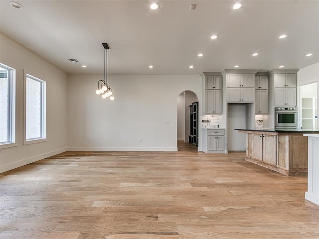 kitchen featuring visible vents, arched walkways, light wood-type flooring, pendant lighting, and recessed lighting