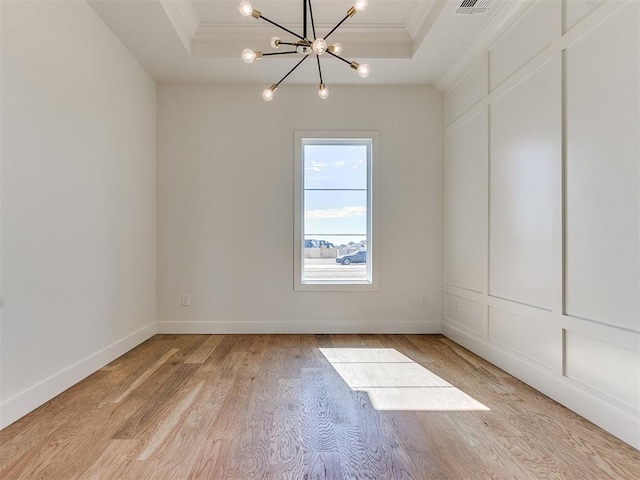 spare room with light wood-style flooring, visible vents, baseboards, ornamental molding, and a tray ceiling