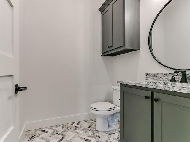 half bath featuring toilet, baseboards, and vanity