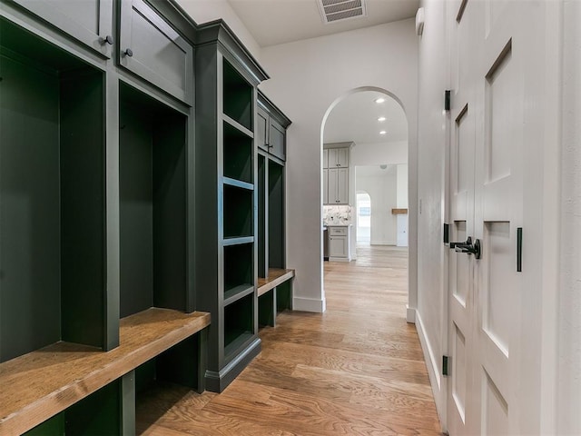 mudroom featuring light wood finished floors, visible vents, arched walkways, and recessed lighting