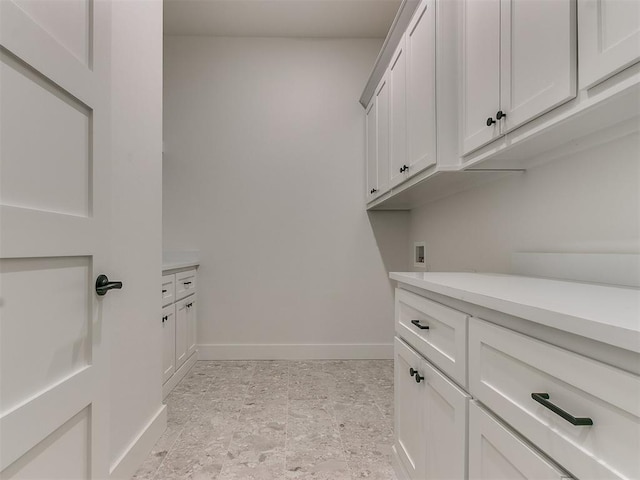 clothes washing area featuring hookup for a washing machine, cabinet space, and baseboards