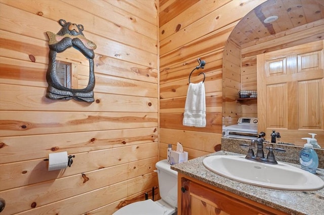 bathroom featuring wooden walls, vanity, and toilet