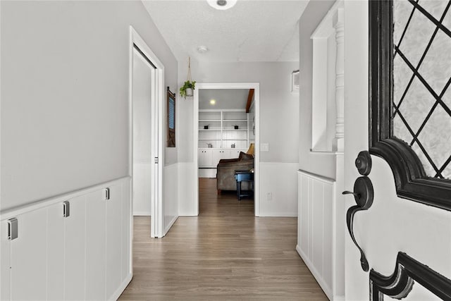 hallway featuring a textured ceiling, dark hardwood / wood-style flooring, and built in features