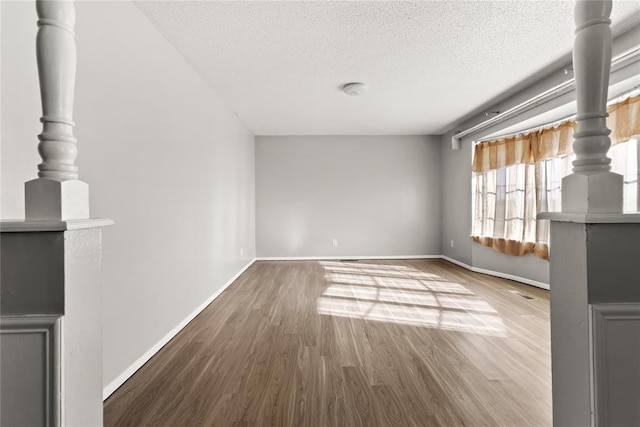 unfurnished living room with wood-type flooring and a textured ceiling