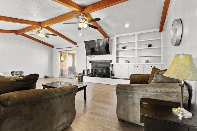 living room with light hardwood / wood-style flooring, vaulted ceiling with beams, ceiling fan, a fireplace, and a textured ceiling