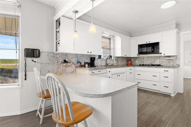 kitchen with kitchen peninsula, a kitchen bar, backsplash, decorative light fixtures, and white cabinets