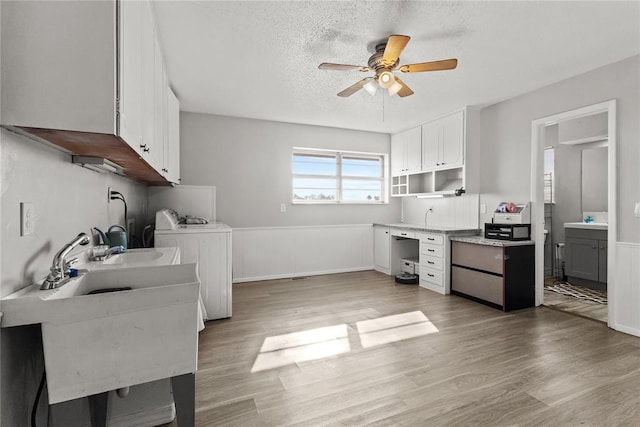 kitchen featuring a textured ceiling, washer and clothes dryer, ceiling fan, light hardwood / wood-style flooring, and white cabinetry