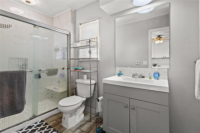 bathroom with ceiling fan, toilet, a shower with door, and vanity