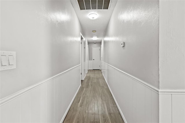 hallway featuring wood-type flooring and a textured ceiling