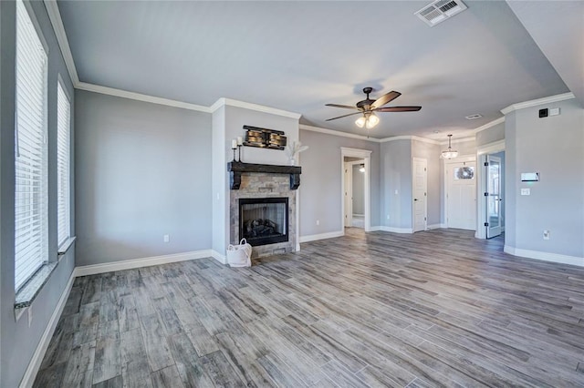 unfurnished living room with hardwood / wood-style floors, a stone fireplace, ceiling fan, ornamental molding, and plenty of natural light