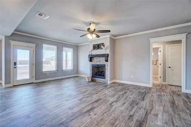 unfurnished living room with ceiling fan, light hardwood / wood-style floors, a stone fireplace, and crown molding