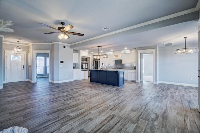 unfurnished living room with ceiling fan, sink, wood-type flooring, and ornamental molding