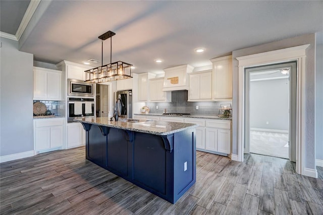 kitchen with white cabinetry, stainless steel appliances, and an island with sink