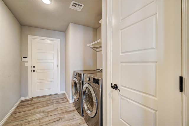 clothes washing area featuring light hardwood / wood-style floors and washing machine and clothes dryer