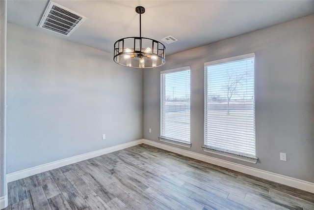 unfurnished room featuring hardwood / wood-style floors and an inviting chandelier