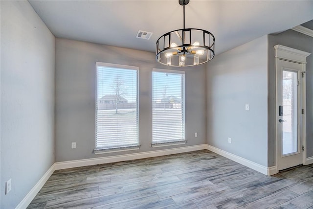 empty room featuring a notable chandelier and light hardwood / wood-style floors