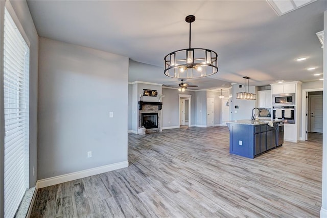 kitchen featuring pendant lighting, blue cabinets, an island with sink, appliances with stainless steel finishes, and white cabinetry