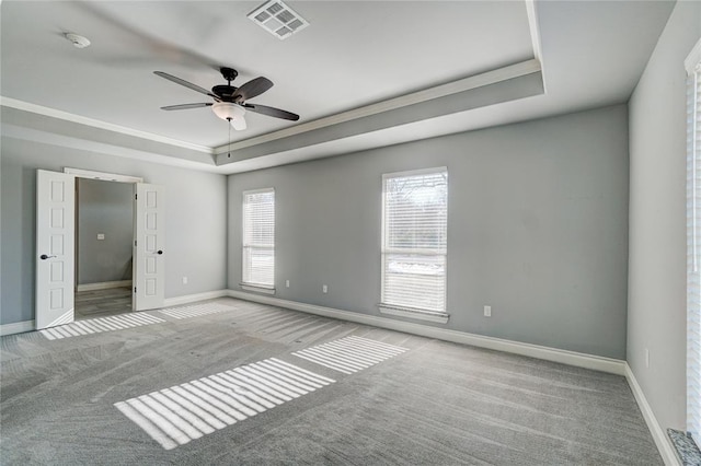 empty room featuring ceiling fan, a raised ceiling, ornamental molding, and light carpet