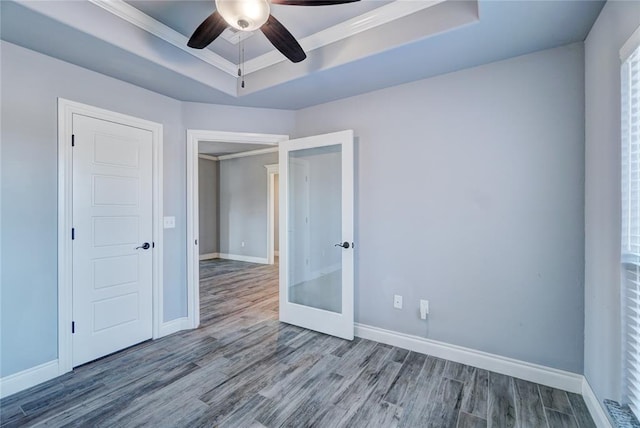 unfurnished bedroom with french doors, a raised ceiling, crown molding, hardwood / wood-style flooring, and ceiling fan