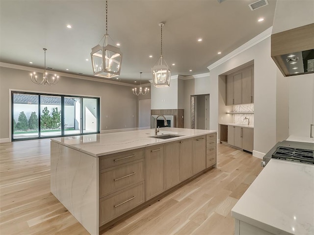 kitchen with a large island with sink, light brown cabinets, and hanging light fixtures