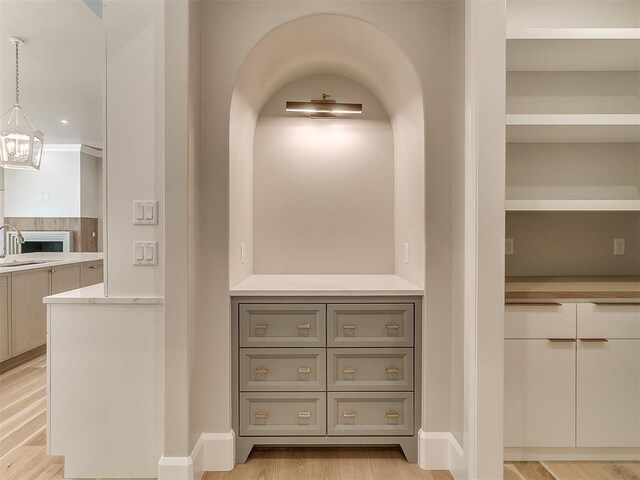 interior space featuring light hardwood / wood-style floors, hanging light fixtures, gray cabinetry, and sink