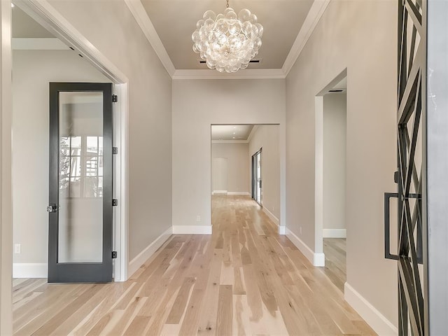 hallway featuring light hardwood / wood-style floors, ornamental molding, and an inviting chandelier