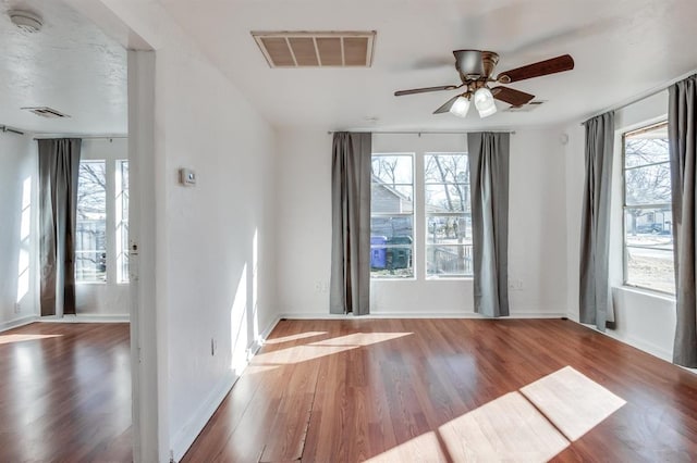 spare room with ceiling fan, a healthy amount of sunlight, and hardwood / wood-style floors