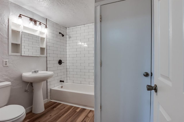 full bathroom featuring sink, hardwood / wood-style flooring, a textured ceiling, toilet, and tiled shower / bath