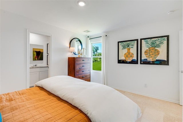 carpeted bedroom featuring ensuite bathroom and sink