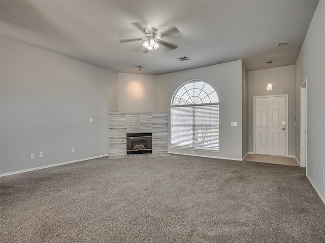 unfurnished living room with carpet flooring, a tile fireplace, and ceiling fan