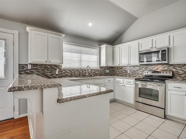 kitchen featuring white cabinetry, stainless steel appliances, kitchen peninsula, lofted ceiling, and light tile patterned floors