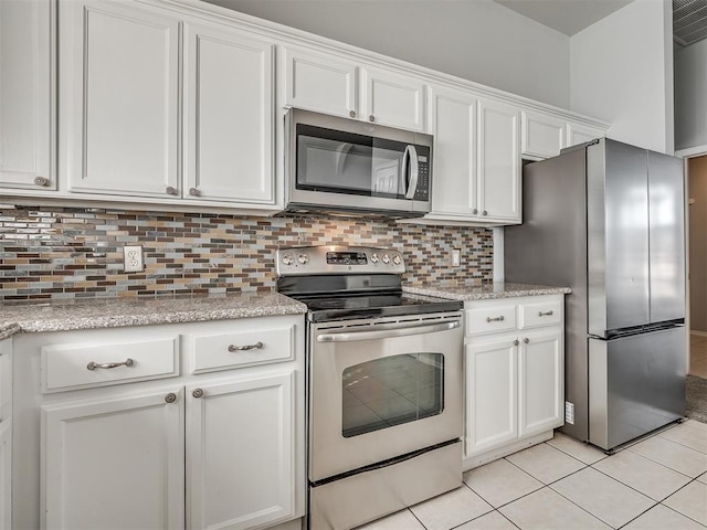 kitchen with decorative backsplash, white cabinets, stainless steel appliances, and light tile patterned floors