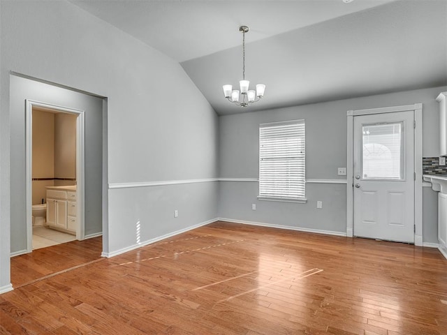 interior space featuring light wood-type flooring, lofted ceiling, and an inviting chandelier