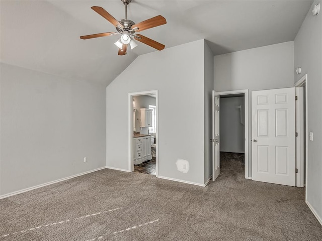 unfurnished bedroom featuring ensuite bath, ceiling fan, a walk in closet, a closet, and dark carpet