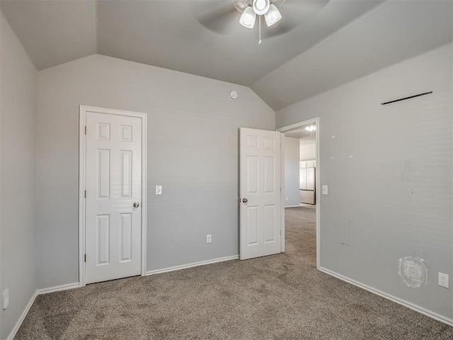 unfurnished bedroom featuring carpet flooring, ceiling fan, white fridge, and vaulted ceiling