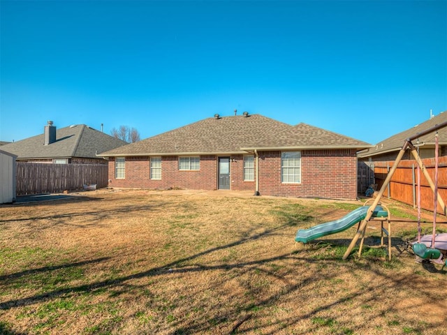 back of property with a playground and a yard