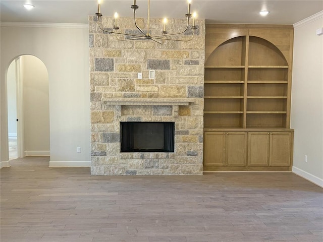 unfurnished living room featuring crown molding, a fireplace, built in features, and light wood-type flooring