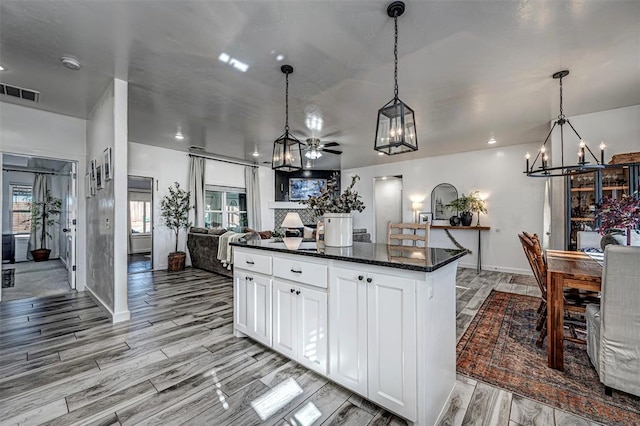 kitchen featuring ceiling fan, a center island, hanging light fixtures, dark stone counters, and white cabinets