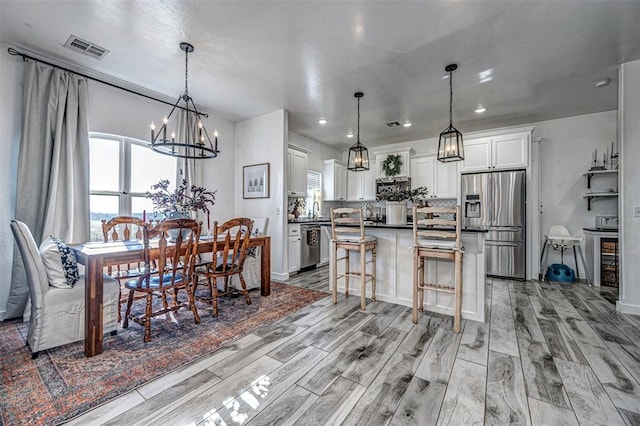 dining space featuring light hardwood / wood-style floors, sink, and an inviting chandelier