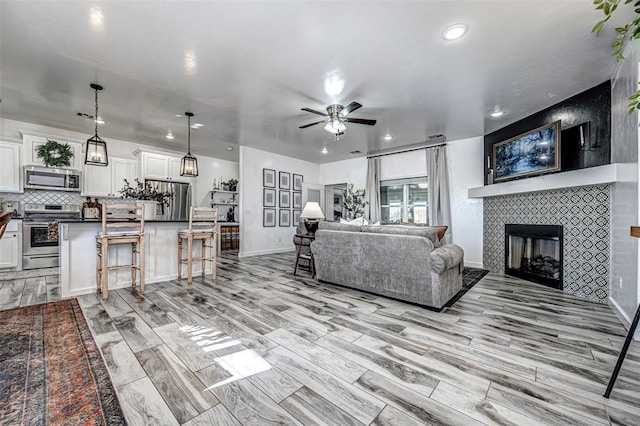 living room with ceiling fan, a fireplace, and light hardwood / wood-style floors