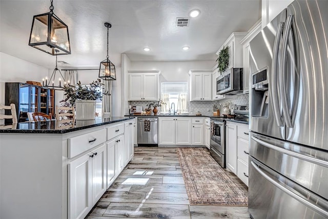 kitchen with pendant lighting, tasteful backsplash, a kitchen island, white cabinetry, and stainless steel appliances