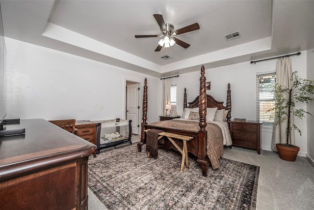 carpeted bedroom featuring ceiling fan and a raised ceiling