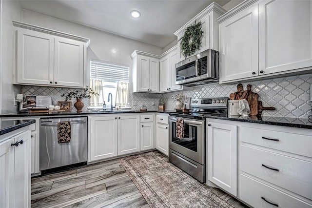 kitchen with white cabinetry, sink, stainless steel appliances, and light wood-type flooring