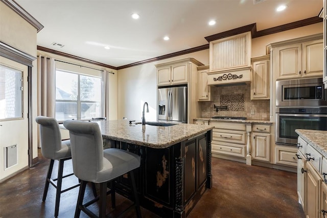 kitchen with decorative backsplash, appliances with stainless steel finishes, light stone counters, a breakfast bar, and an island with sink