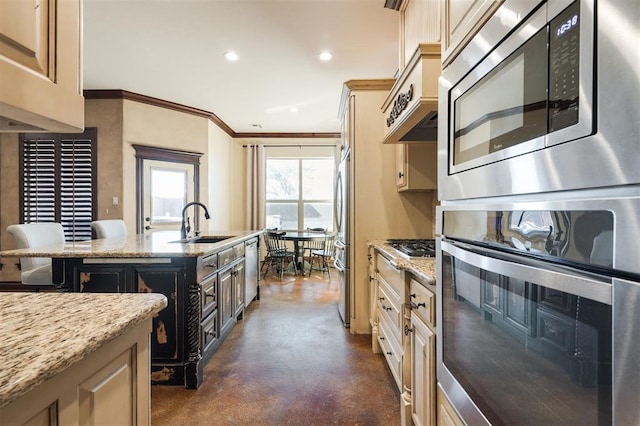 kitchen featuring light stone countertops, ornamental molding, stainless steel appliances, a kitchen island with sink, and sink