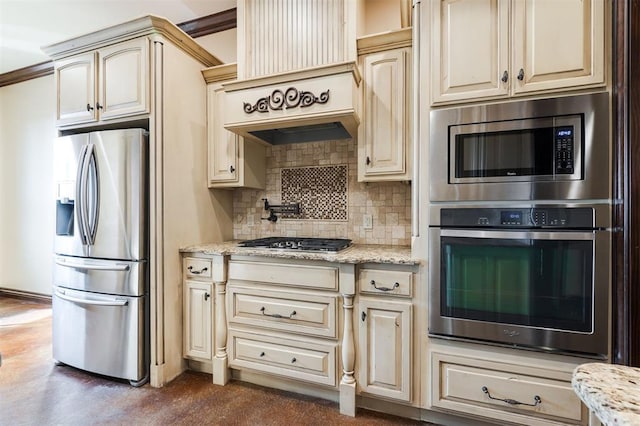 kitchen with custom exhaust hood, cream cabinets, decorative backsplash, appliances with stainless steel finishes, and light stone counters