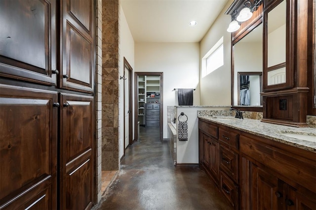 bathroom with a tub to relax in, vanity, and concrete floors