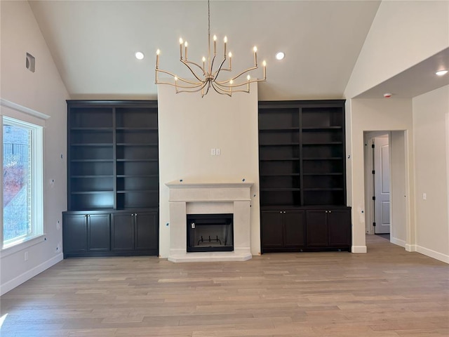 unfurnished living room with built in shelves, lofted ceiling, and light wood-type flooring